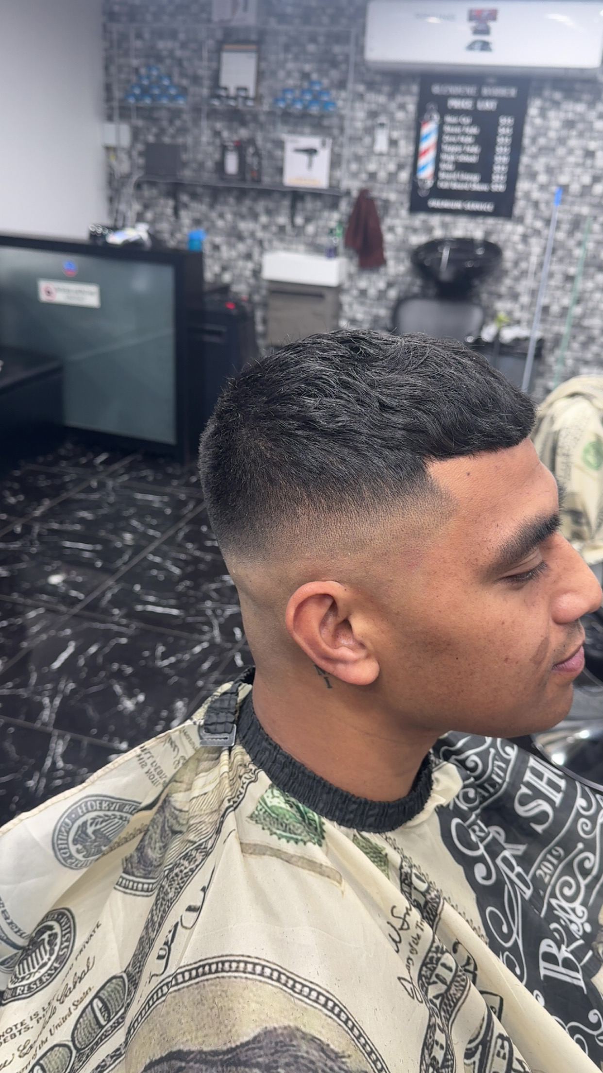 Short dark hair with a clean taper and shaped hairline